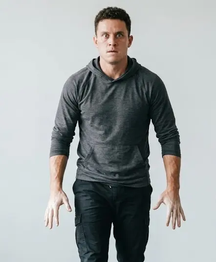 Person in a freeze response — body completely still, expression tense and locked, rigid posture, stopped mid-movement under threat