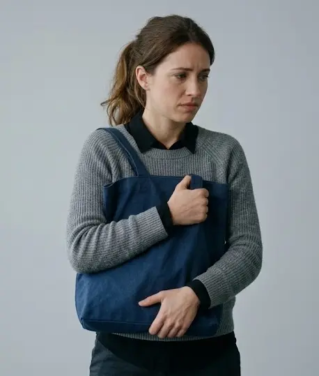 Woman clutching bag against chest as object barrier body language