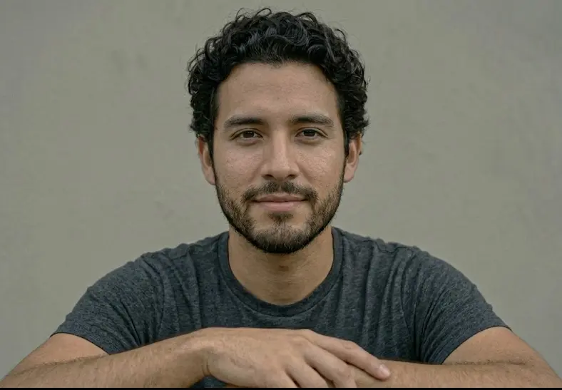 Man leaning slightly forward with chest fully facing the camera, direct relaxed gaze and open posture showing ventral fronting and genuine engagement